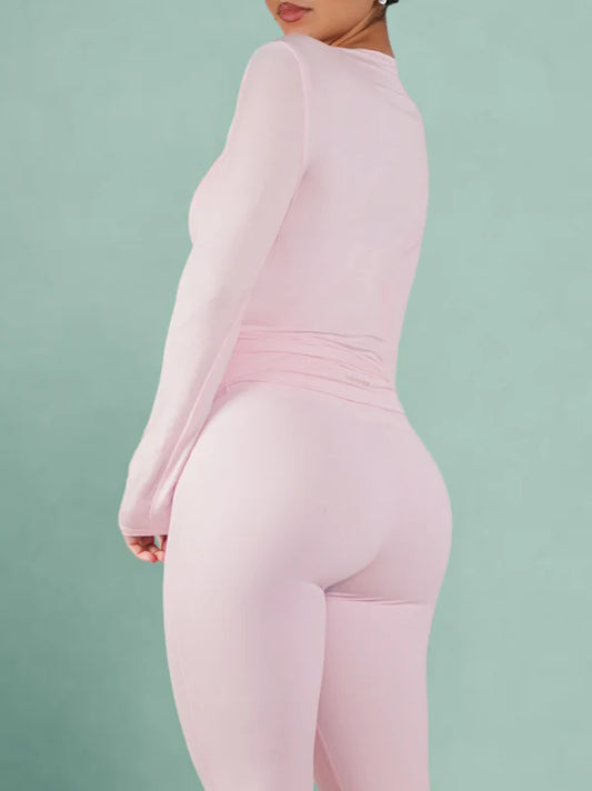 Person wearing a pink long-sleeve top and leggings on a light green background