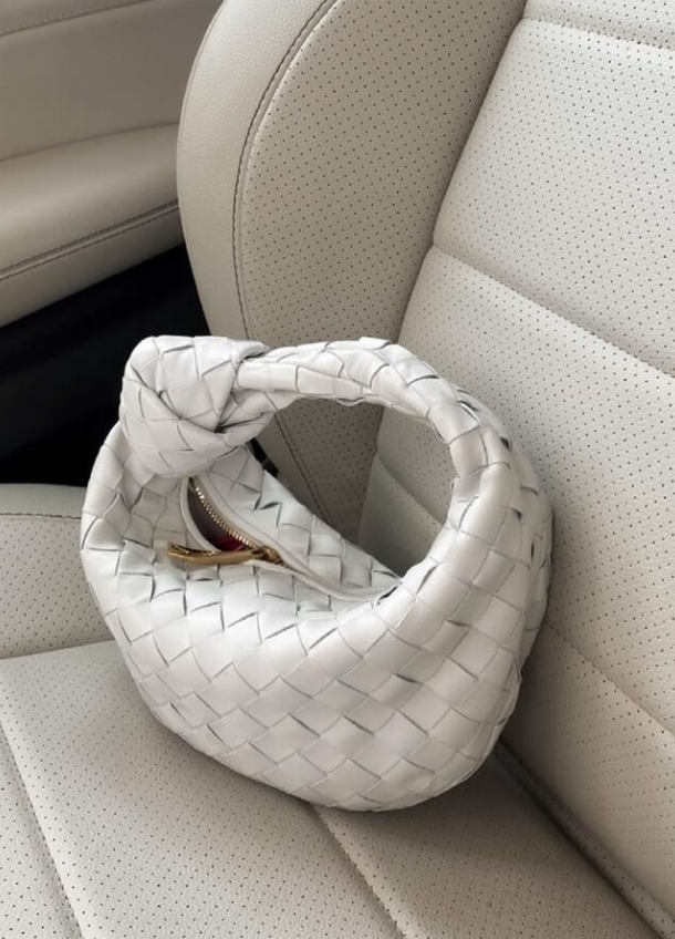 White woven handbag on a beige car seat