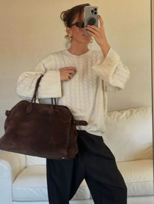 Person holding a brown bag in front of a white couch