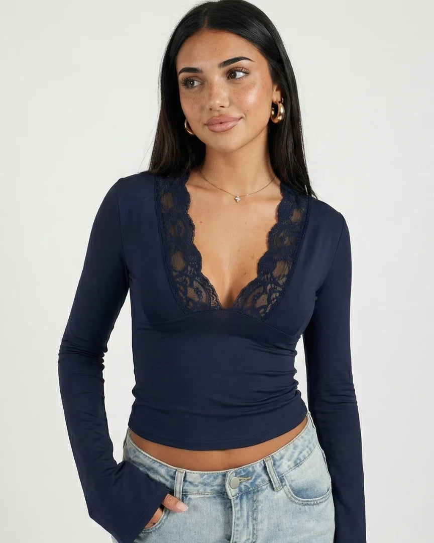 Woman wearing a navy long-sleeve top with lace details on a white background