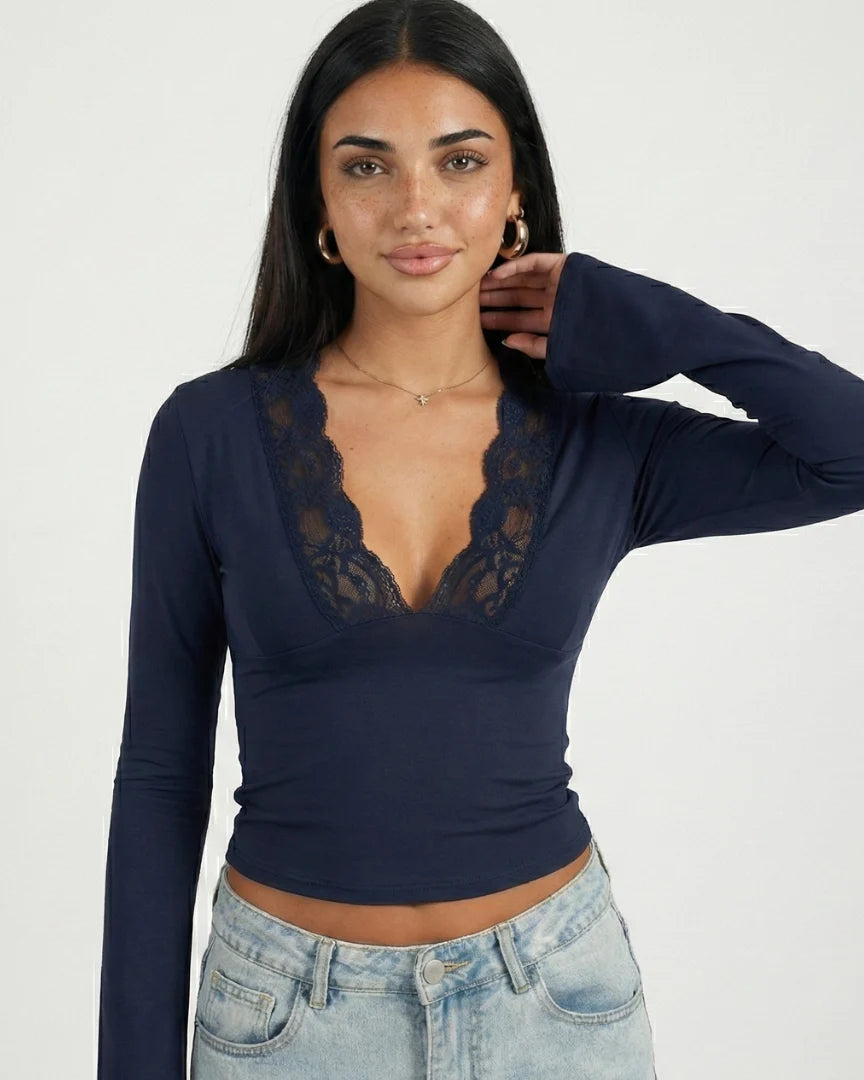 Woman wearing a navy long-sleeve top with lace details on a white background