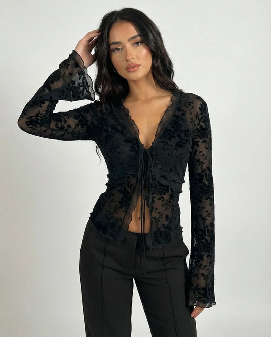 Woman wearing a black lace top and black pants on a white background