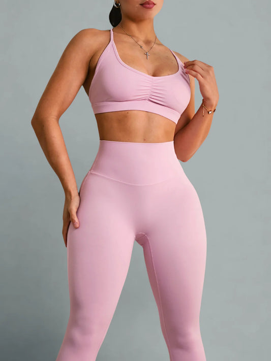 Person wearing a pink sports bra and leggings set on a gray background