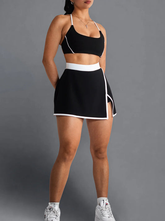 Woman wearing a black sports bra and skirt set on a gray background
