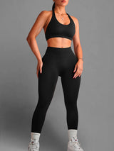 Person wearing a black sports bra and leggings set on a gray background