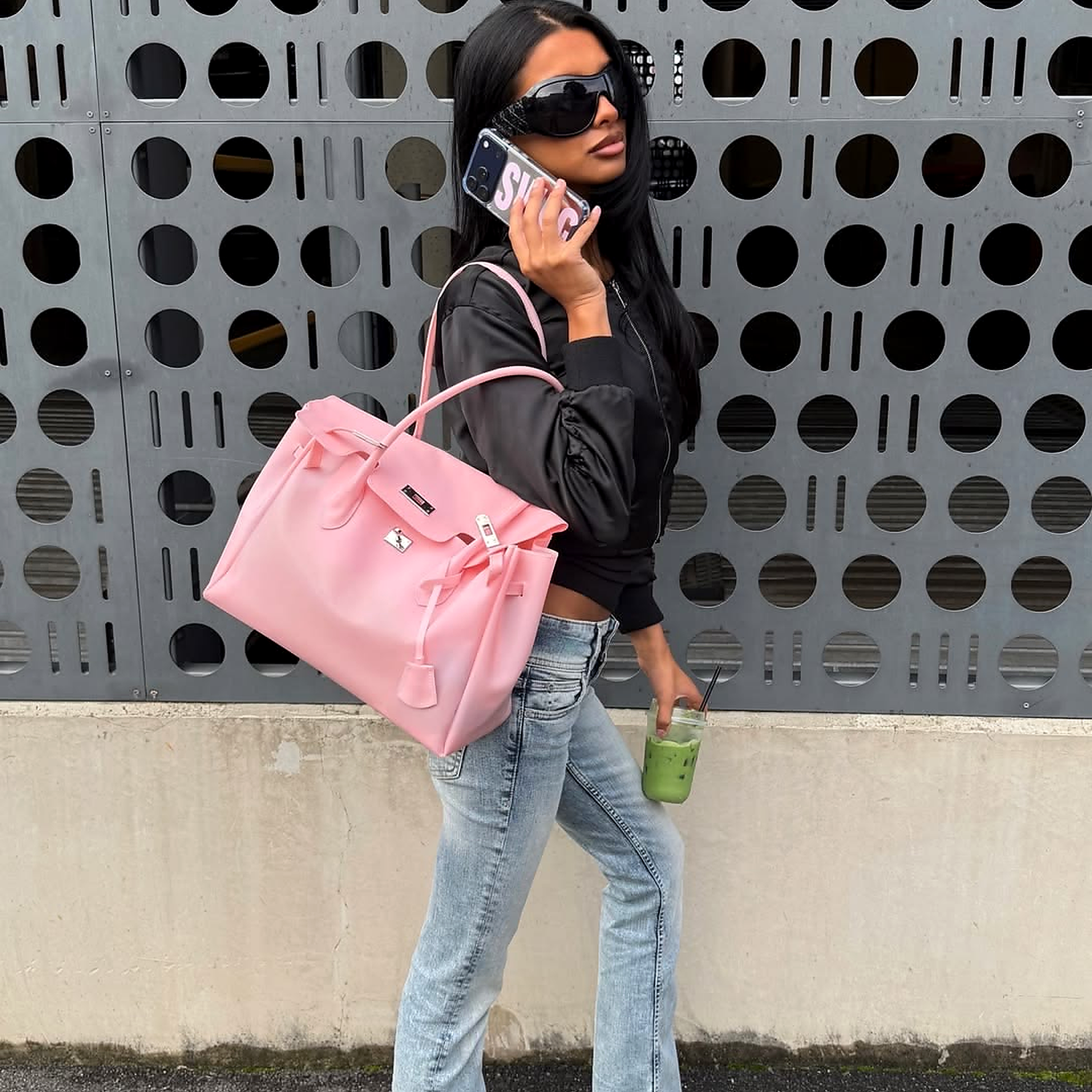 Woman holding a jelly firkin bag and a phone, standing against a patterned wall