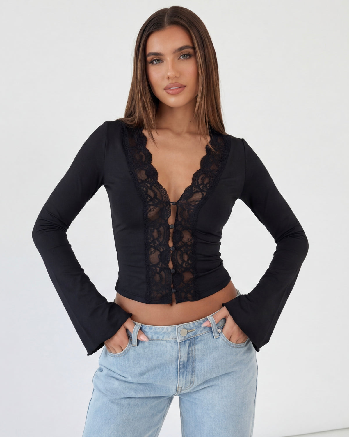 Woman wearing a black lace top and light blue jeans on a white background