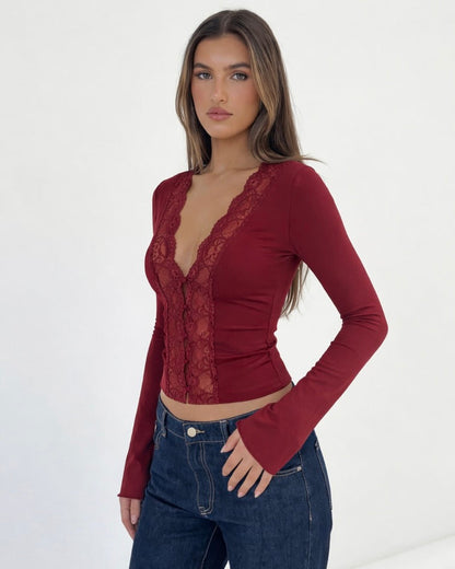 Woman wearing a red lace top and blue jeans on a white background