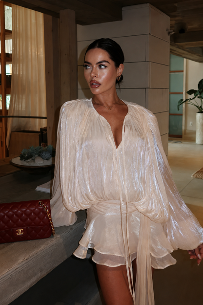 Ruffled mini dress worn by a woman sitting on a stone ledge indoors