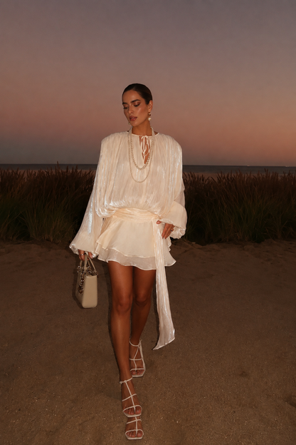 Beige apricot Ruffled mini dress worn by a woman standing in a desert landscape at sunset