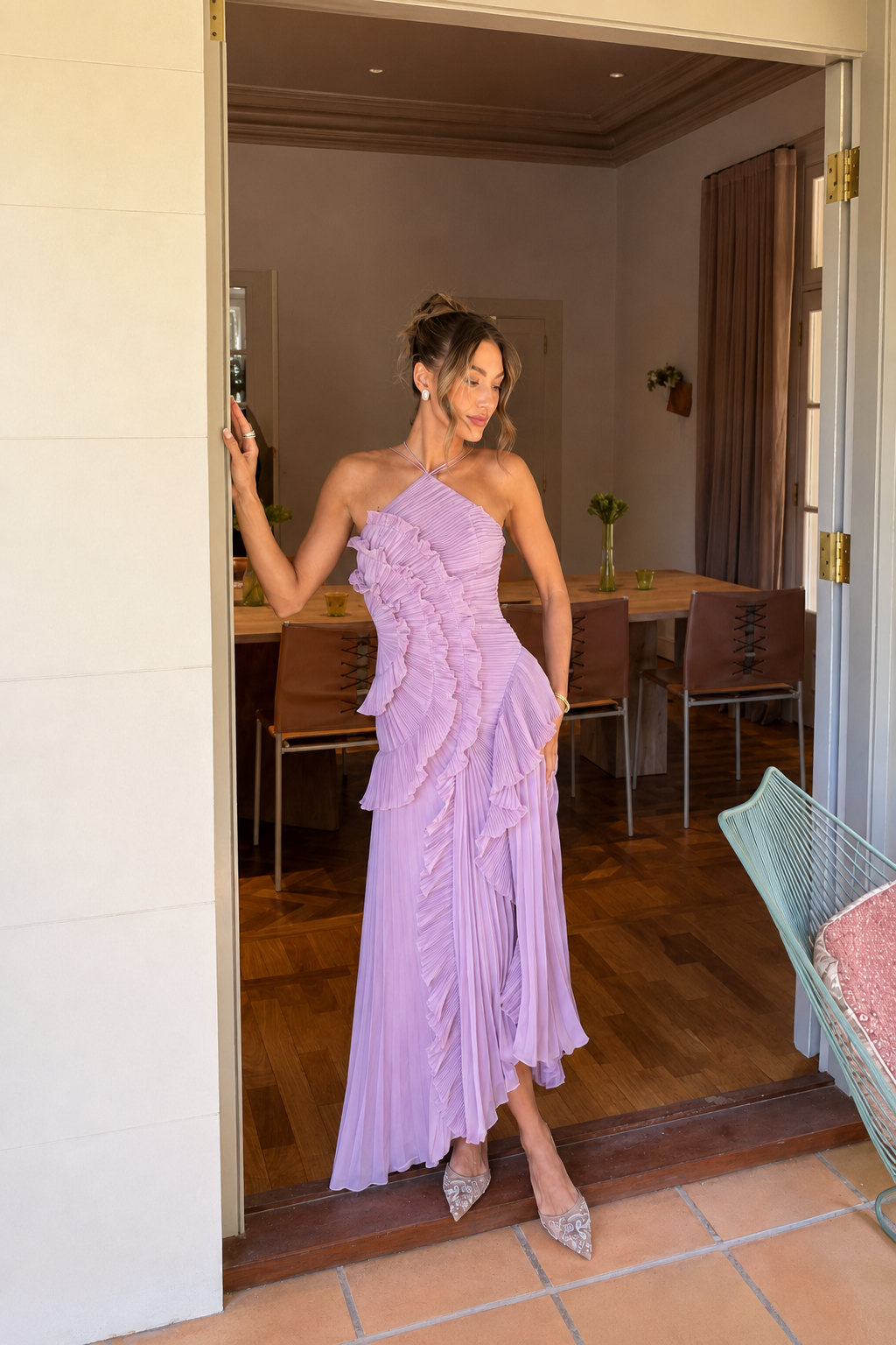 A woman models a lavender ruffled maxi dress in a doorway, with a dining room and wooden floor visible in the background.