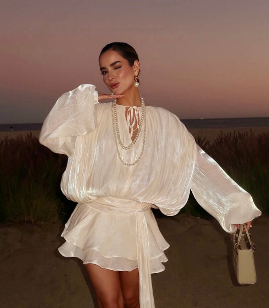 Woman in a trending ruffled mini dress standing in a field with a sunset background