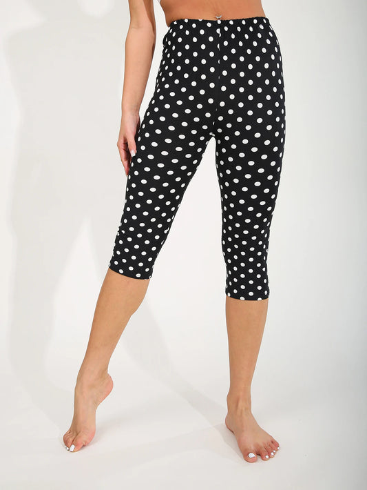 Black capri leggings with white polka dots worn by a person on a white background