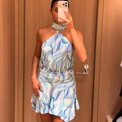 Woman taking a mirror selfie wearing a colorful halter neck dress.