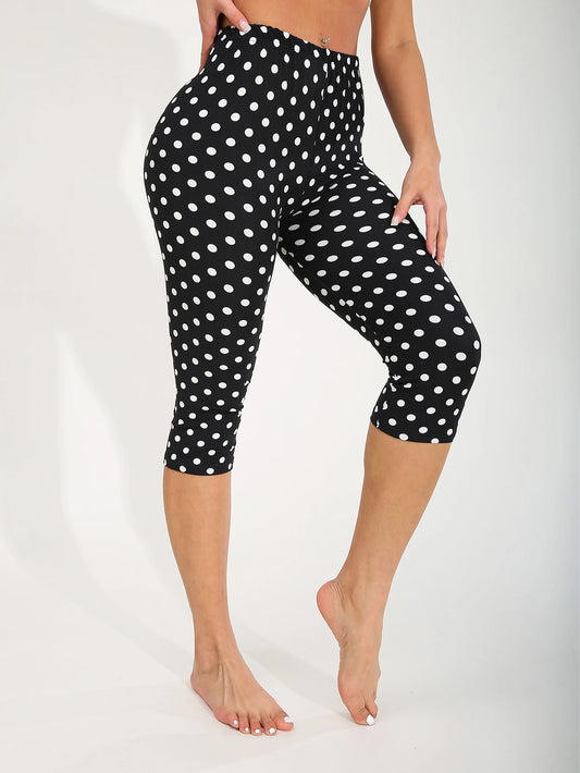 Black capri leggings with white polka dots worn by a person on a white background