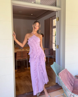 Lavender one shoulder ruffle pleated maxi dress worn by a woman standing in a doorway