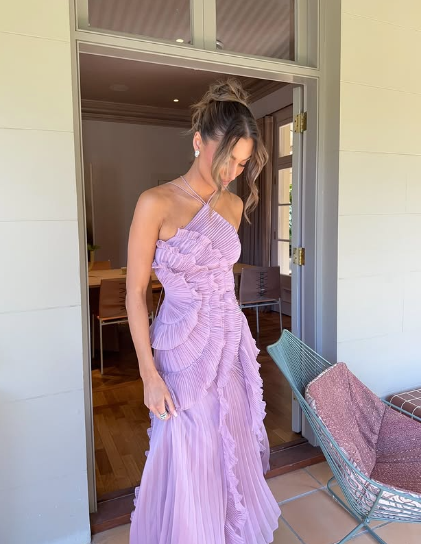Woman in a lavender dress standing in a doorway.