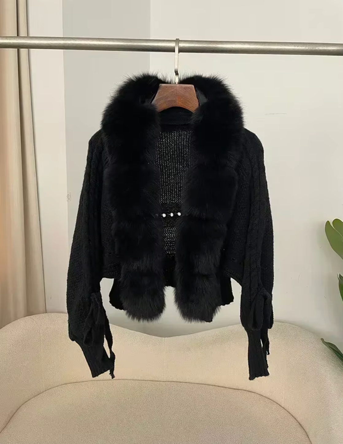 Black fur jacket with a hanger on a white background