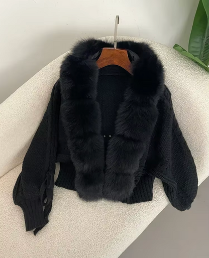 Black fur jacket with a hood on a beige surface