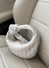White woven handbag on a beige car seat