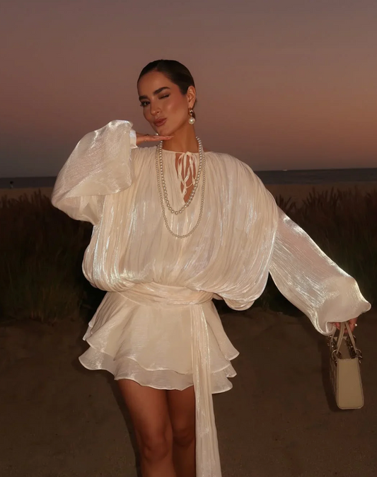 Woman in a white dress standing against a sunset sky