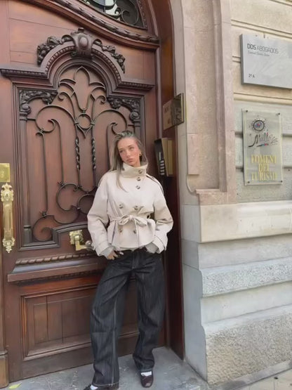 Model walking on the street wearing a trench coat with baggy denim trousers